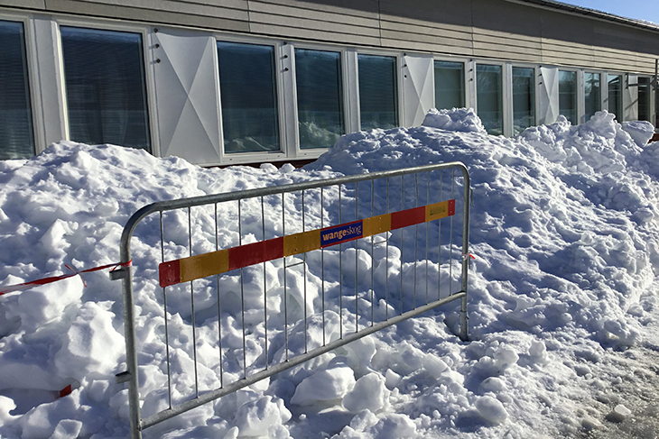 Stora snöhögar nedanför skolans tak.