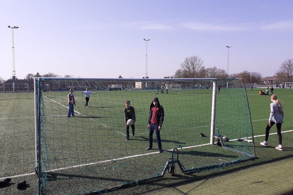 En stor fotbollsplan och några elever som leker på den.